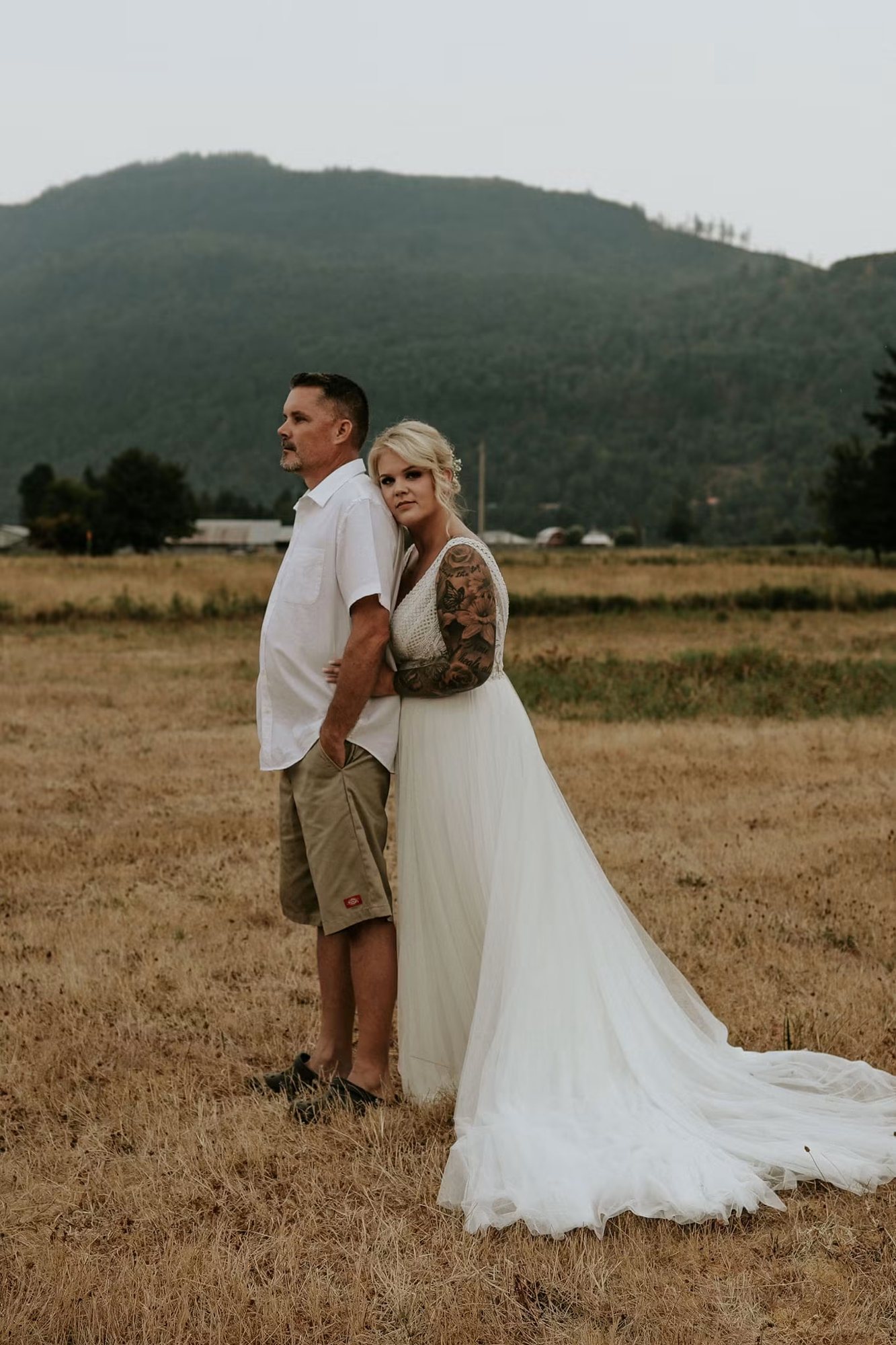 A bride and groom standing together on a mountain ridge at golden hour near Chilliwack, BC